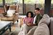 © Wavebreak Media - Happy diverse couple sitting on sofa in living room using tablet