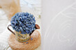 Home decor. A sprig of blue hydrangea in a decorative watering can for flowers on a round wicker straw stand.