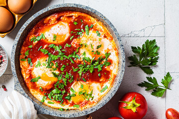 Wall Mural - Traditional Israeli shakshuka in gray frying pan. Fried eggs in tomato sauce, close-up.