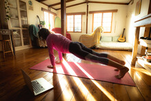 Mixed Race Woman Practicing Yoga, Doing Push Ups In Sunny Living Room