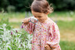 © Syda Productions - childhood, leisure and people concept - happy little baby girl with magnifier looking at flowers in summer garden