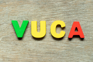 Wall Mural - Color alphabet letter in word VUCA (abbreviation of Volatility, uncertainty, complexity and ambiguity) on wood background