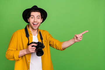 Poster - Portrait of young smiling excited photographer point finger copyspace ad recommend isolated on green color background