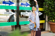 © Cristian Borrego  - Beautiful Caucasian woman hailing a taxi at the exit of the airport with a suitcase in her hand.