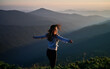 Young slim woman enjoying fresh air and beauty nature in the mountains. Concept of freedom and harmony with nature.