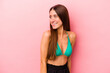 © Asier - Young caucasian woman wearing bikini isolated on pink background looks aside smiling, cheerful and pleasant.