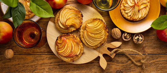 Poster - Mini Apple pie tartlets with walnut on wooden table. Delicious dessert for autumn winter dinner.Top view.