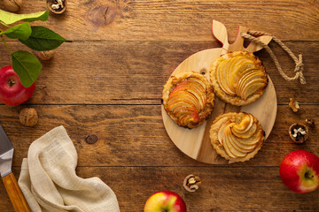 Poster - Mini Apple pie tartlets with walnut on wooden table. Delicious dessert for autumn winter dinner.Top view.