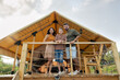 © pressmaster - Three family members in casualwear having rest by glamping house in non-urban environment