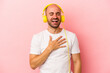 © Asier - Young caucasian bald man listening to music isolated on pink background  laughs out loudly keeping hand on chest.