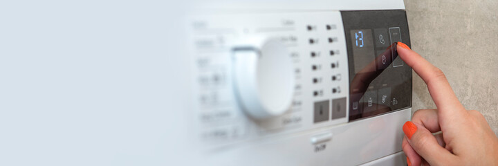 washing machine. the hand turns on the washing machine or the choice of the washing program. washing