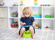 Toddler girl sitting on a potty with the tablet. Potty training 
