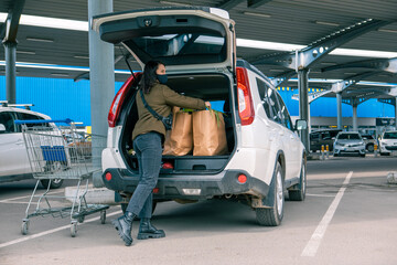 Wall Mural - woman put bags with products in car trunk after grocery store