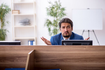 Young male employee sitting at workplace