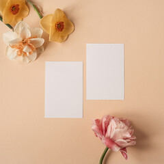 Wall Mural - Blank paper sheet card with mockup copy space and narcissus and rose flowers on neutral dusty peachy background. Minimal aesthetic business brand template. Flat lay, top view