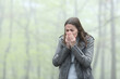 © PheelingsMedia - Woman sneezing in a cold foggy park