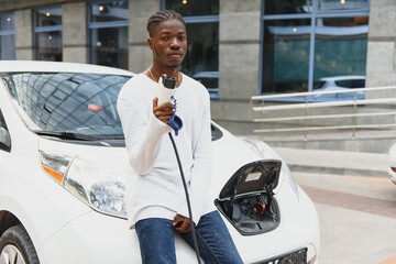 Wall Mural - African American man charging his electric car.