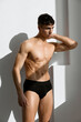 © SHOTPRIME STUDIO - handsome man with a pumped-up body in black panties on a light background