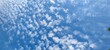 White high clouds in the blue sky. A summer sunny day against the background of a blue sky, white cumulus and cirrus clouds are falling. Clouds stretched across the sky.