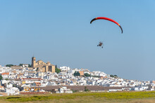 Paramotor Vehicle Flying In The Sky With A City Behind