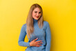 © Asier - Young russian woman isolated on yellow background touches tummy, smiles gently, eating and satisfaction concept.