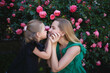 © Aleksandra Iarosh - mom hugs her little daughter against the background of a rose bush