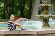 Teenage girl in striped dress sitting at the fountain