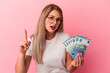 © Asier - Young russian woman holding bills isolated on pink background having an idea, inspiration concept.