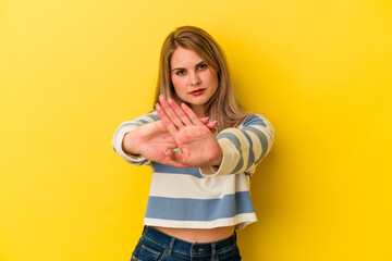 Young russian woman isolated on yellow background standing with outstretched hand showing stop sign, preventing you.