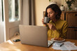 © Wavebreak Media - Caucasian woman in living room, sitting at table working, using laptop