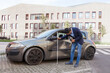 © khosrork - Side view of brunette male auto insurance adjuster inspecting a vehicle that has been in an accident wreck, wearing jeans and jacket, assesses the damage to the car. Outdoor shot.