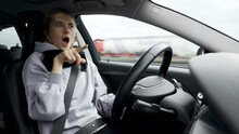 Young Woman With Natural Look Driving A Passenger Car On A German Highway. The Young Woman Shows Various Emotional Reactions To The Traffic Event.