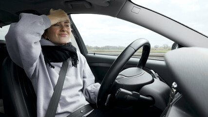 Wall Mural - Young woman with natural look driving a passenger car on a German highway. The young woman shows various emotional reactions to the traffic event.