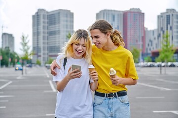 Wall Mural - Happy laughing couple of teenagers walking hugging together in city