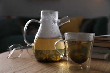 Poster - Glass teapot and cup of hot tea on wooden table in living room. Cozy home atmosphere