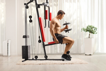 Canvas Print - odybuilder shirtless sitting and exercising on a fitness machine indoors