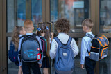 Fototapeta Londyn - Little schoolchildren open the school door