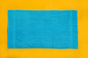 Wall Mural - Light blue beach towel on yellow background, top view