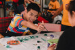 © GAYSORN - Handicapped teenager boy on wheelchair with happy face doing art work with friends, Lifestyle of smart disabled kid learning activity in special children school, Mental health classroom concept.