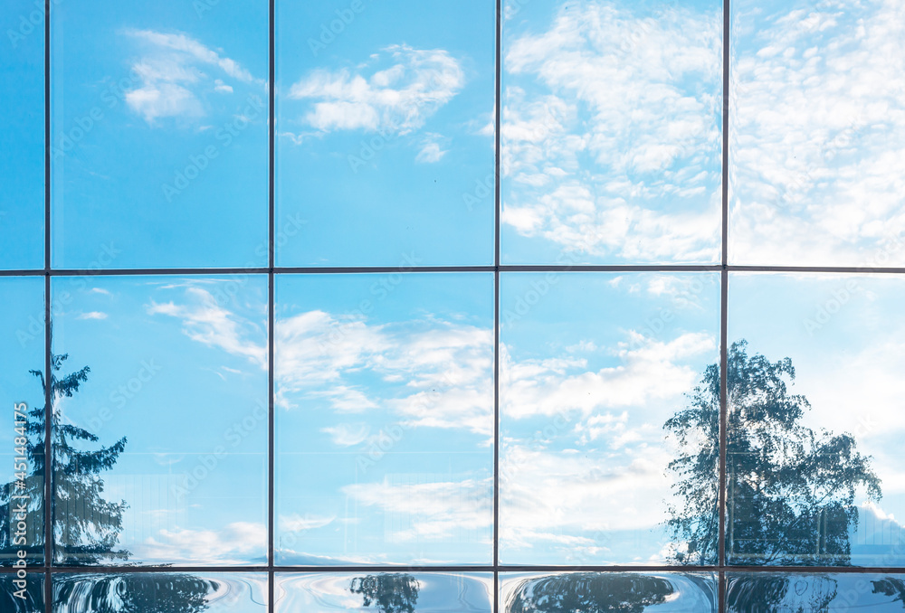 Blue sky, clouds and trees reflection in grid of glass window of modern ...