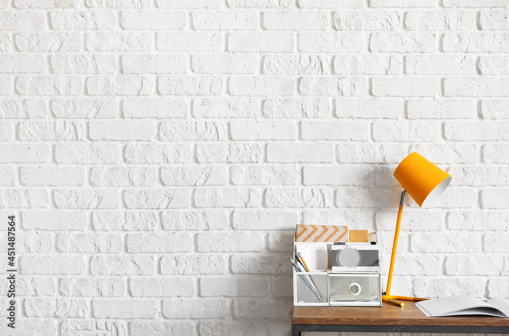 Table with lamp and organizer near brick wall