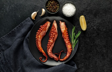 Wall Mural - grilled octopus tentacles, on a dark plate on a stone background