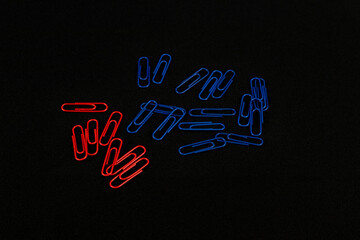 Poster - Red and blue paper clips on a black background