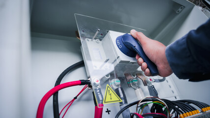 The technician of the solar plant twists the breaker handle of the combiner box to ON to power the system after performing a fault check. Cut off the electricity before working for safety