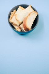 Poster - Vertical shot of bread slices on a bowl isolated on blue background