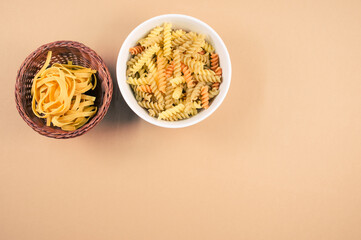 Poster - Top view of tri-color rotini and fettuccine pasta on a bowl isolated on brown background