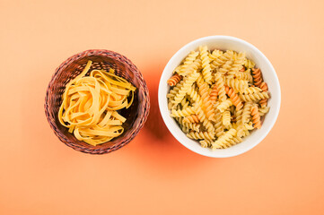 Sticker - Top view of tri-color rotini and fettuccine pasta on a bowl isolated on an orange background