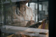 © Prathankarnpap - View through window of businesswoman holding pen and making note on notebook.