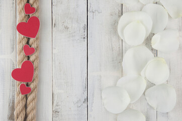 Wall Mural - hemp rope wyth red hearts and white rose petals on the white wood table. Birthday. Wedding. Holiday. Top view. Copy space