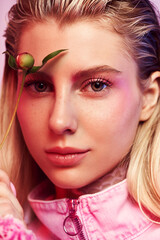 Close up portrait of beautiful blonde woman with flower near eye